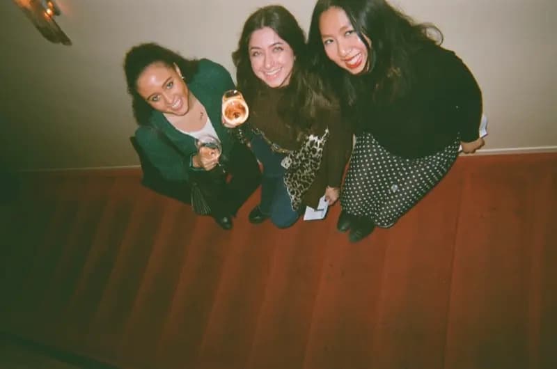 Three friends smiling up at the camera at a Wingmate event